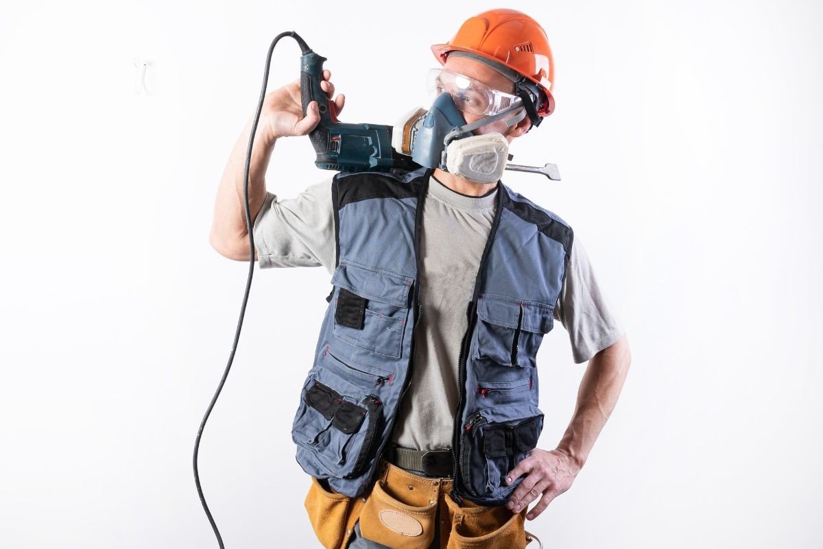 homem equipado com epis segurando ferramenta eletrica