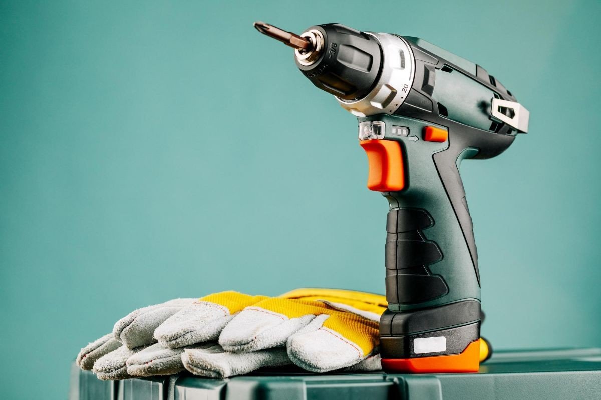 parafusadeira em bancada ao lado de par de luvas